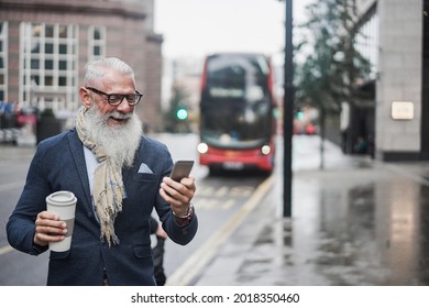 Senior Business Man Going To Work Drinking Coffee With London Bus Station In Background - Focus On Face