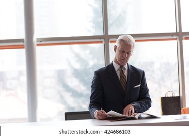 Senior Business Man Reading Magazine At Modern Bright Office