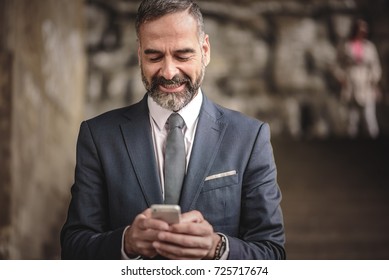 Senior Business Man Receiving A Happy Message On His Cell Phone, Outdoor Urban Area