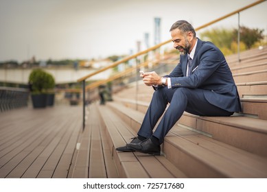 Senior Business Man Receiving A Happy Message On His Cell Phone, Outdoor Urban Area