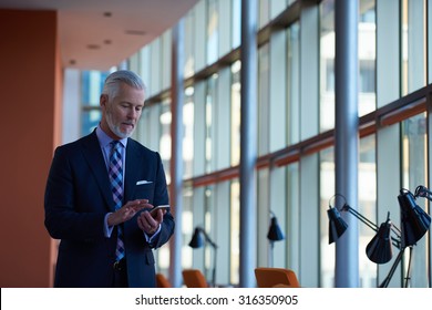 Senior Business Man Talk On Mobile Phone  At Modern Bright Office Interior