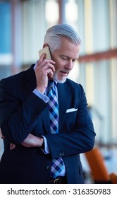 Senior Business Man Talk On Mobile Phone  At Modern Bright Office Interior