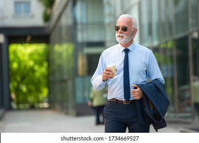 Senior business man walking and holding cup of coffee - Powered by Shutterstock