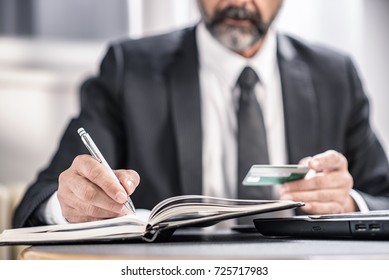 Senior Business Man Writing Down Credit Card Information In His Personal Agenda