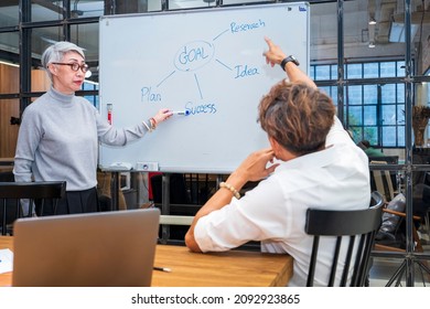 Senior Business Team Leader Is Guiding Young Member To Business Success By Showing Chart For Goal Achievement For Startup And Creativity Project