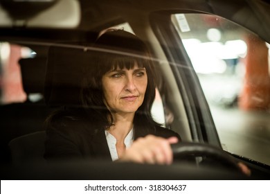 Senior Business Woman Driving Car At Night - View Through Front Window