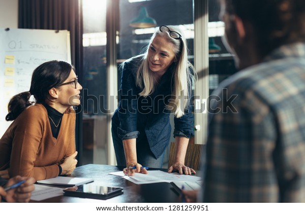 Senior business woman explaining business\
matters to her team in a boardroom. Mature manager planning new\
strategy with colleagues in\
meeting.