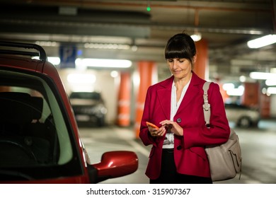 Senior Business Woman Looking To Her Mobile Phone While Standing At Her Car