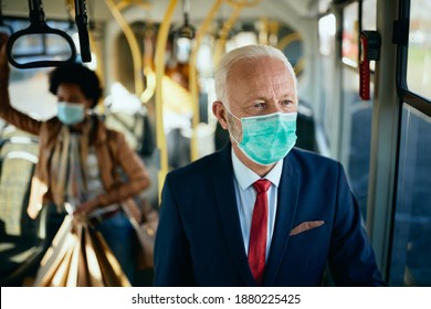 Senior businessman commuting to work by bus while wearing face mask due to COVID-19 pandemic.   - Powered by Shutterstock