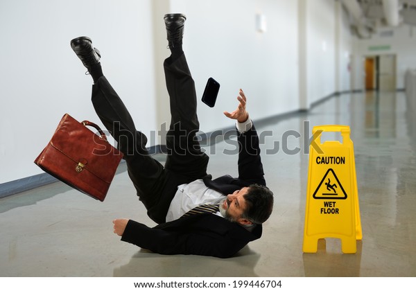 Senior
businessman falling near caution sign in
hallway