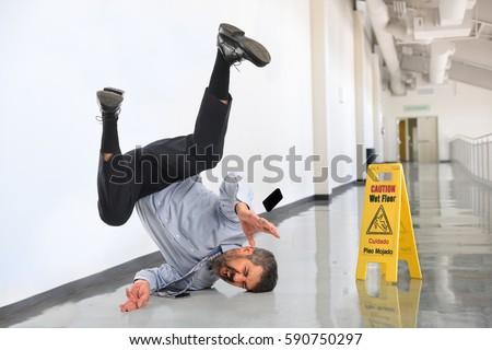 Senior businessman falling on wet floor inside office building