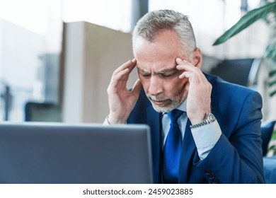 Senior businessman feeling headache while doing distance work in coffee shop working remote on laptop computer. Stressful life. Experience frequent headaches or migraine attacks. - Powered by Shutterstock