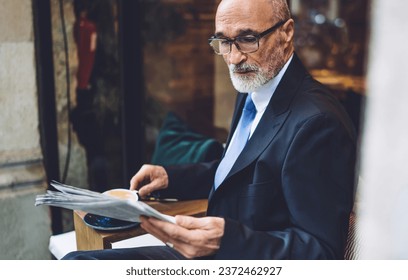 Senior businessman in glasses with coffee mug reading newspaper - Powered by Shutterstock