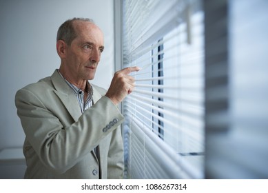 Senior Businessman Looking Outside Through Blinds Stock Photo ...