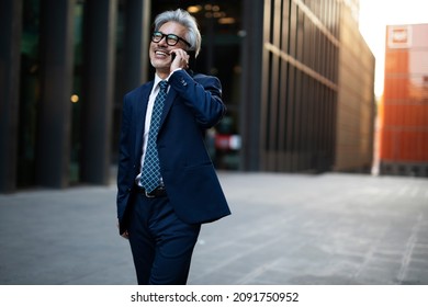 Senior businessman outdoors. Middle-aged businessman talking to the phone - Powered by Shutterstock