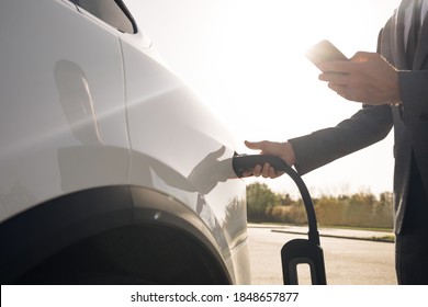 Senior businessman is plugging in power cord to an electric car. Luxury electrical car recharging. Environmentally conscious male charging electric vehicle. Unrecognizable man plugging in electric car - Powered by Shutterstock