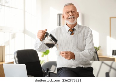 Senior businessman pouring coffee from pot into cup in office - Powered by Shutterstock