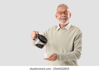 Senior businessman pouring coffee from pot into cup on grey background - Powered by Shutterstock