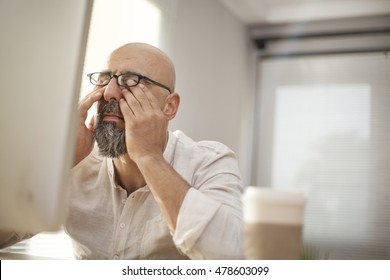Senior businessman rubbing his tired eyes