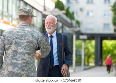 Senior businessman shaking hands with soilder outdoor