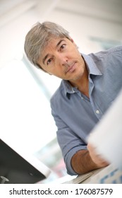 Senior Businessman Sitting In Front Of Desktop