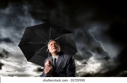 senior businessman with umbrella under a stormy sky