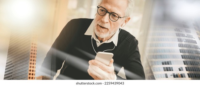 Senior businessman using earphones during conversation on mobile phone; multiple exposure - Shutterstock ID 2259439043