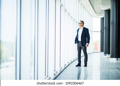 Senior businessman walking in modern office building. Successful business man wearing suit and tie.