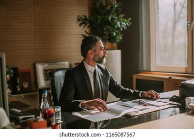 Senior businessman working in modern office at desk - Shutterstock ID 1165087567