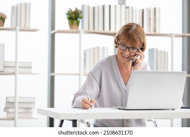 Senior Businesswoman Or Freelance Using Laptop Computer And Talking About Work On Phone