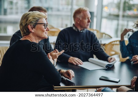 Senior businesswoman sitting in boardroom meeting. Group of business people having a meeting in office.