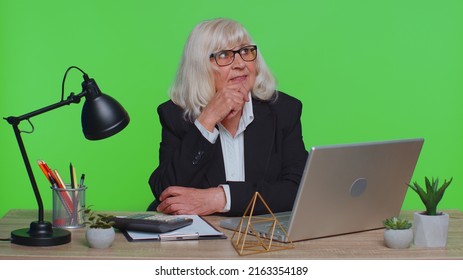 Senior businesswoman in thought and conjectures looking to side, dreaming, imagining something pleasant fantasizing about weekends holidays. Elderly woman isolated on green chroma key studio at office - Powered by Shutterstock