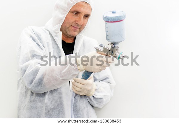 Senior car painter wearing a custom suit ready to
spray paint on a car
