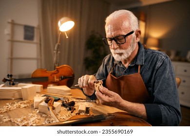 Senior carpenter craftsman carving wood and making violin instrument - Powered by Shutterstock