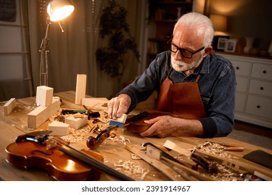 Senior carpenter craftsman making violin instrument