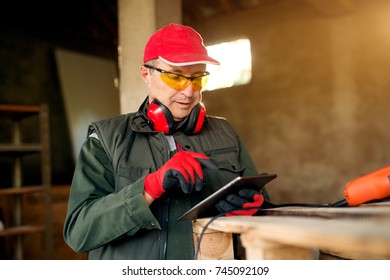 Senior carpenter entrepreneur holding a tablet in the workshop. - Powered by Shutterstock