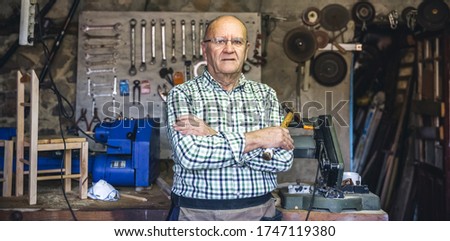 Senior carpenter posing with crossed arms in his workshop
