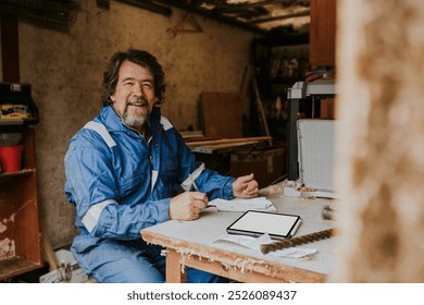 Senior carpenter working in his wood workshop. Middle age man carpentry owner sitting in workshop garage. Senior small business entrepreneur, senior carpenter man working in wood studio - Powered by Shutterstock