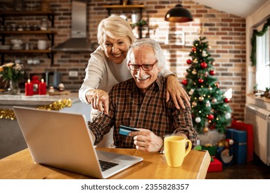 Senior caucasian couple online shopping on their laptop with a credit card during christmas and the new year holidays - Powered by Shutterstock