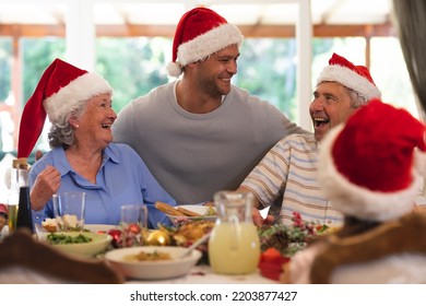 Senior caucasian couple and their adult son sitting at table for dinner together, wearing santa hats, embracing and smiling. quality family time christmas celebration. - Powered by Shutterstock