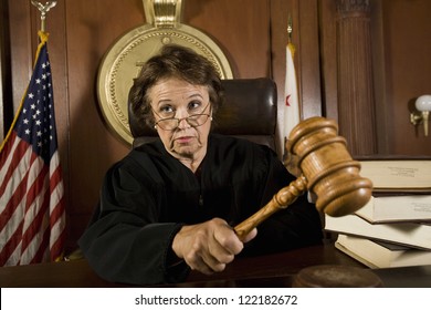 Senior Caucasian Judge Holding Mallet In Courtroom