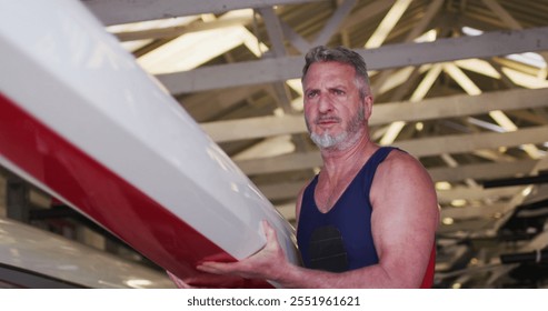 Senior caucasian man carrying a rowing boat. sport retirement leisure hobbies rowing healthy outdoor lifestyle. - Powered by Shutterstock