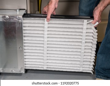 Senior caucasian man changing a folded air filter in the HVAC furnace system in basement of home