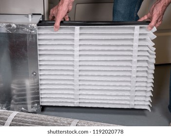 Senior Caucasian Man Changing A Folded Air Filter In The HVAC Furnace System In Basement Of Home