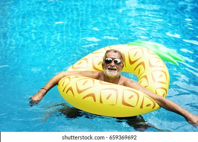 Senior Caucasian Man Floating In The Pool With Inflatable Tube