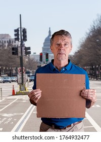 Senior Caucasian Man Holding A Blank Cardboard Sign For Copy Space Message. He Is Composited Into Washington DC Street Scene