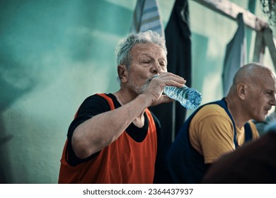 Senior Caucasian man hydrating in the locker room after playing football or soccer - Powered by Shutterstock