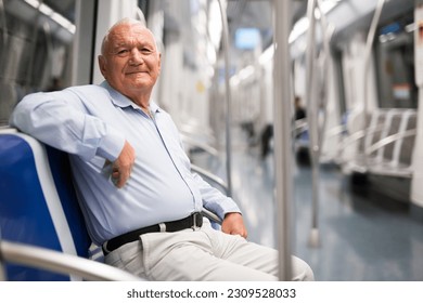 Senior Caucasian man sitting on seat in subway car and looking in camera.