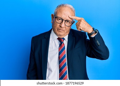 Senior Caucasian Man Wearing Business Suit And Tie Pointing Unhappy To Pimple On Forehead, Ugly Infection Of Blackhead. Acne And Skin Problem 