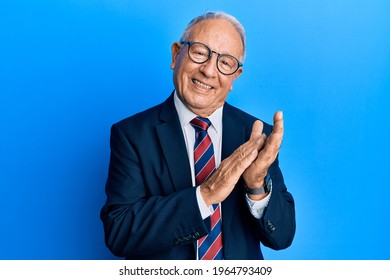 Senior Caucasian Man Wearing Business Suit And Tie Clapping And Applauding Happy And Joyful, Smiling Proud Hands Together 